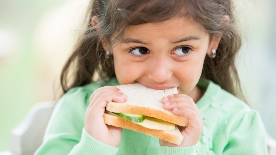 little girl eating a sandwich