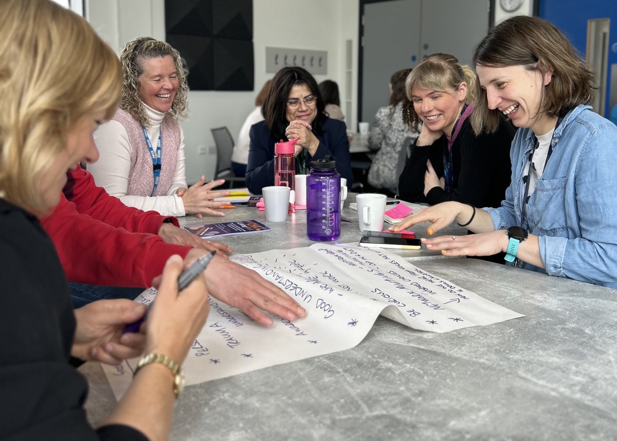 group meeting and smiling around table writing notes