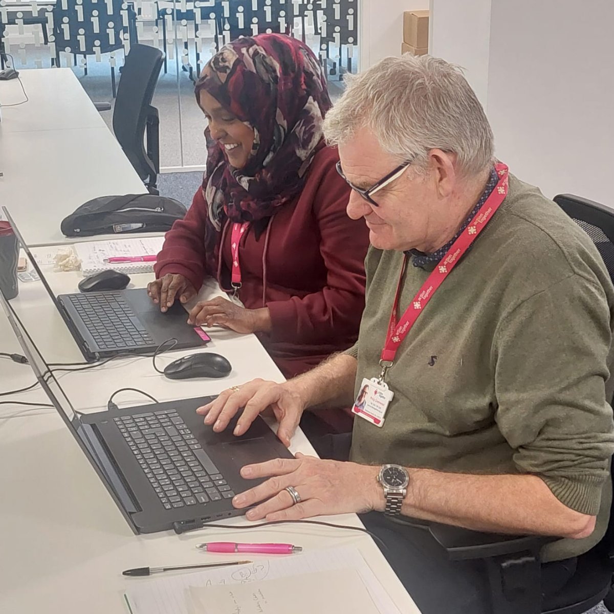 Two people working at laptops - Asma and Phil - Volunteering Support Officers
