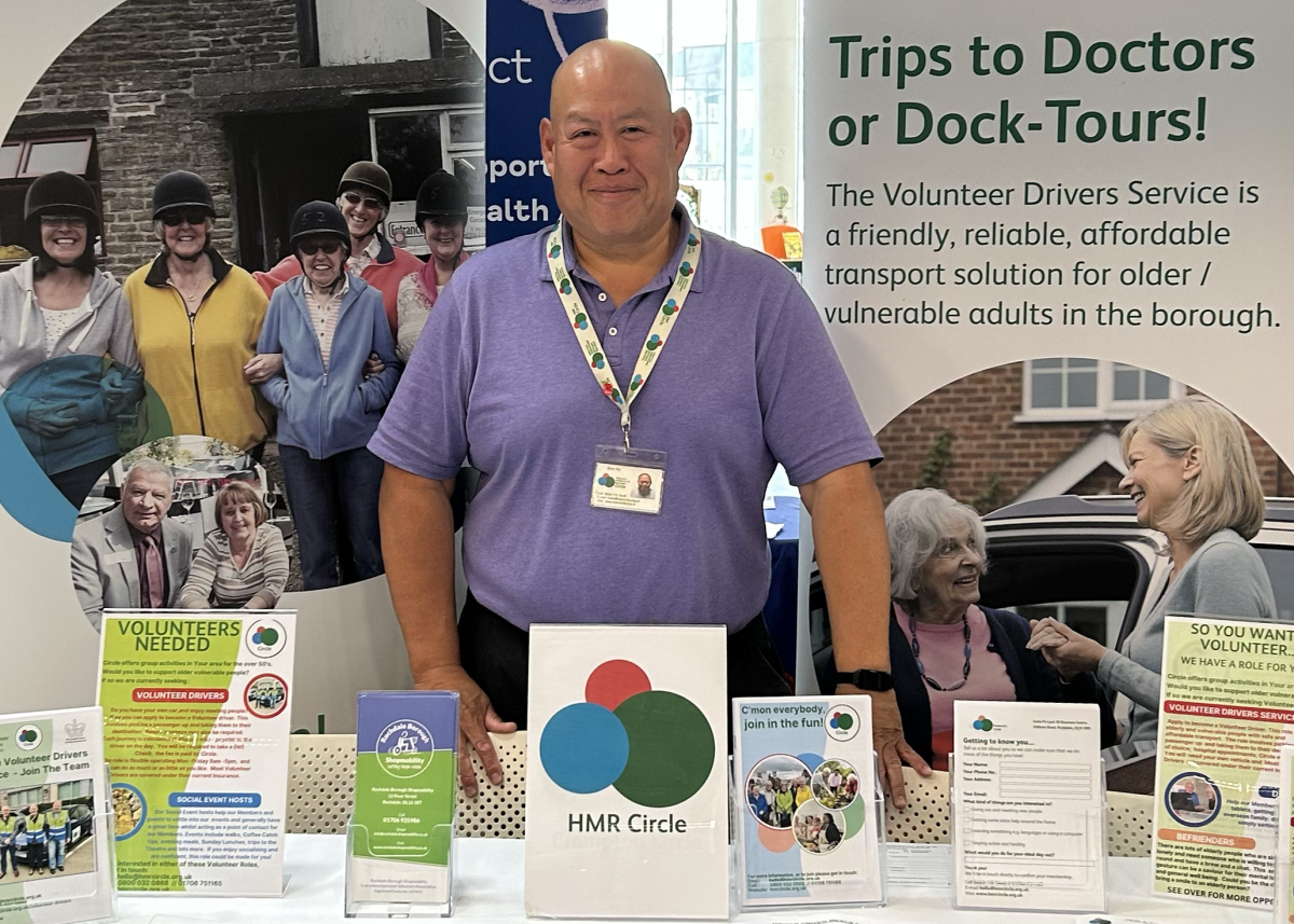 Kim Ho from HMR Circle smiling behind exhibition desk at Volunteer Fair