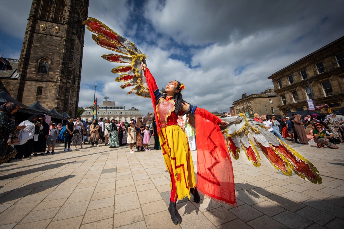 Artistic street performer in creative costume with red and yellow wings