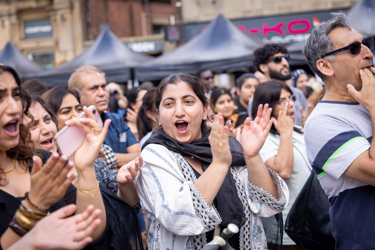 Photo of crowd enjoying street celebrations with focus on a woman smiling and clapping her hands