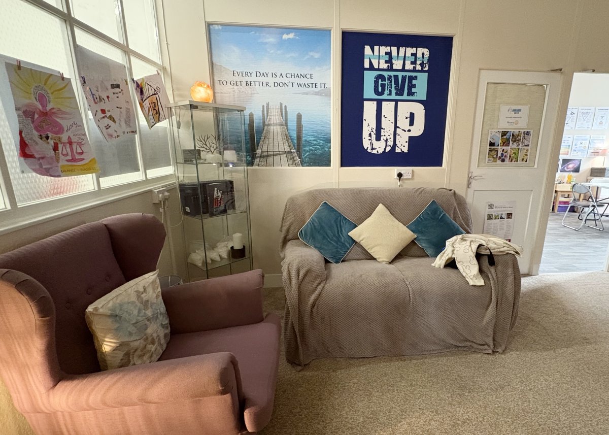 Photo of a cosy room with two sofas and a poster saying 'Never Give Up' on the wall