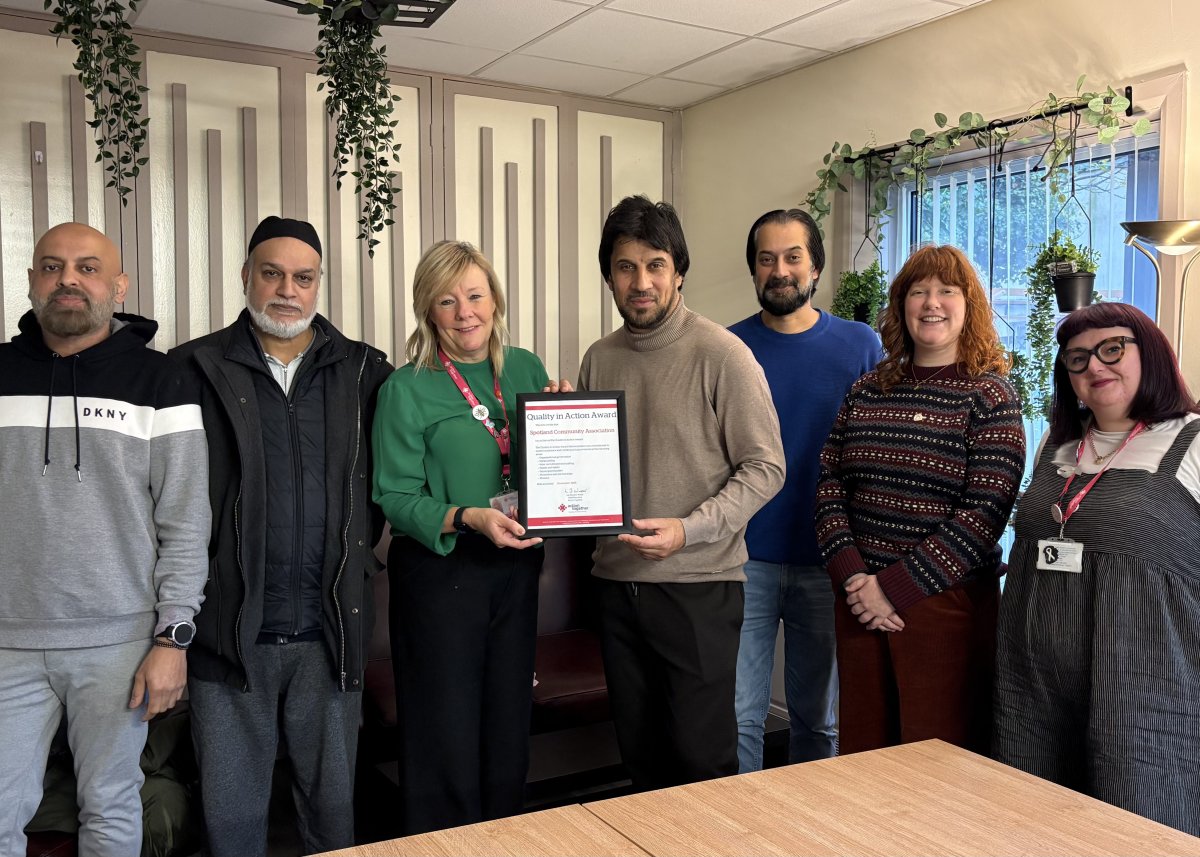 Group photo of Spotland Community Centre team receiving QiAA Award from Julie and Trish