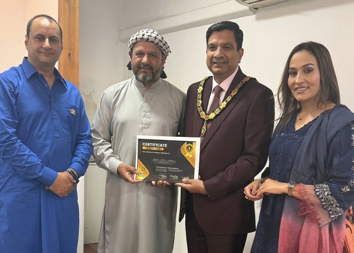 Group of four people smiling with one person being presented with a volunteer appreciation certificate