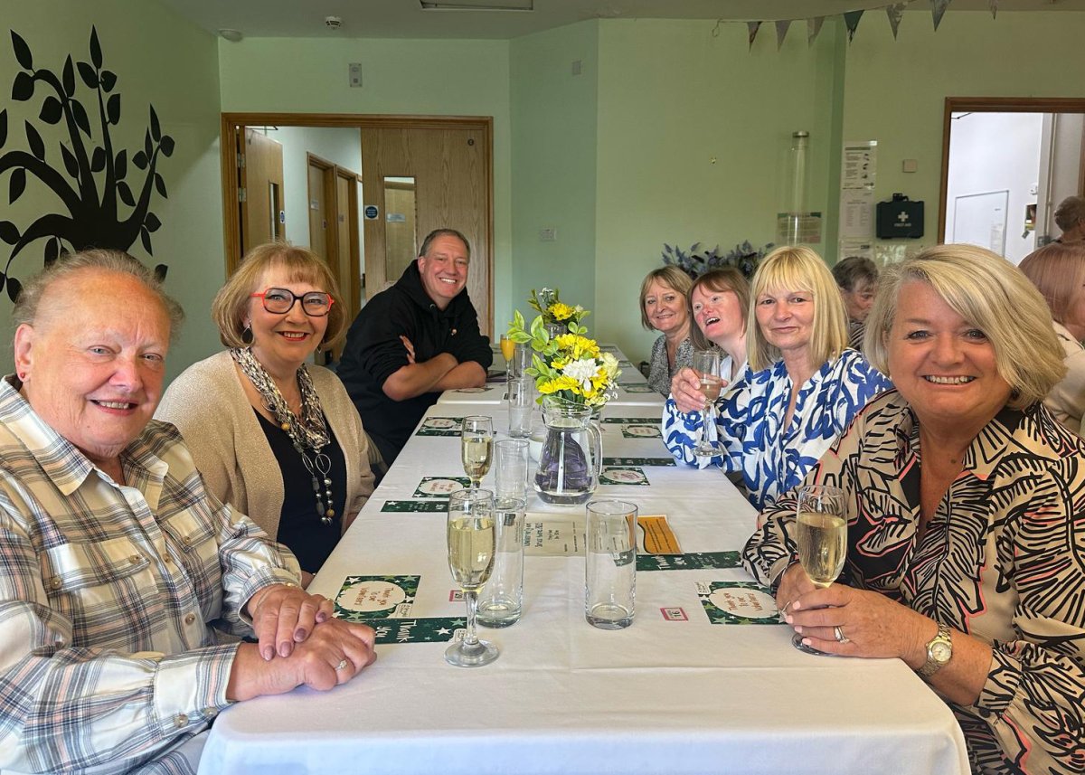 Group of people smiling and seated around a dinner table at Springhill Hospice