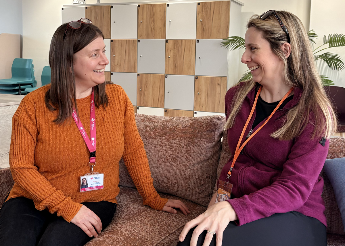Vicky Lomax and Clare Yardley chatting and smiling seated on sofa
