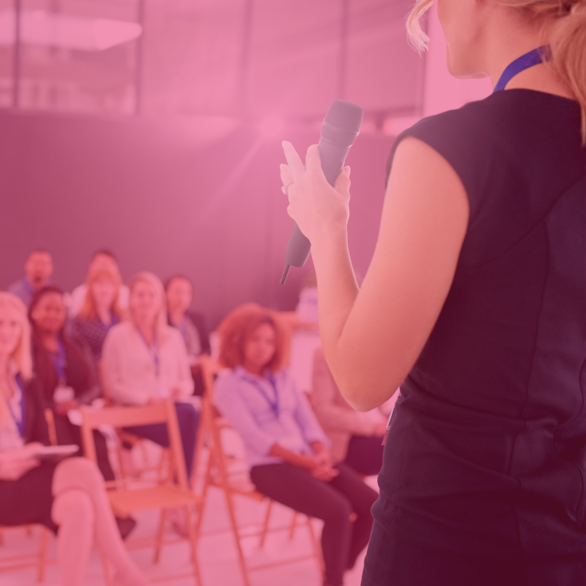 Person presenting with microphone to seated audience